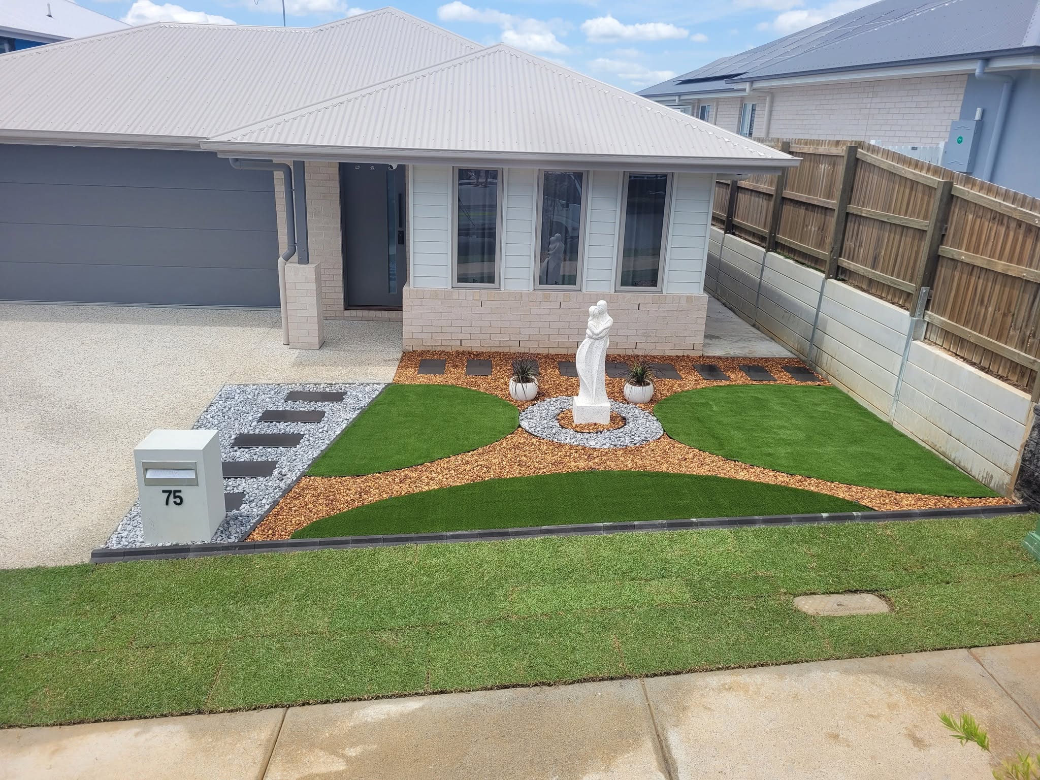 Detailed front yard landscaping with curved turf and stone paths