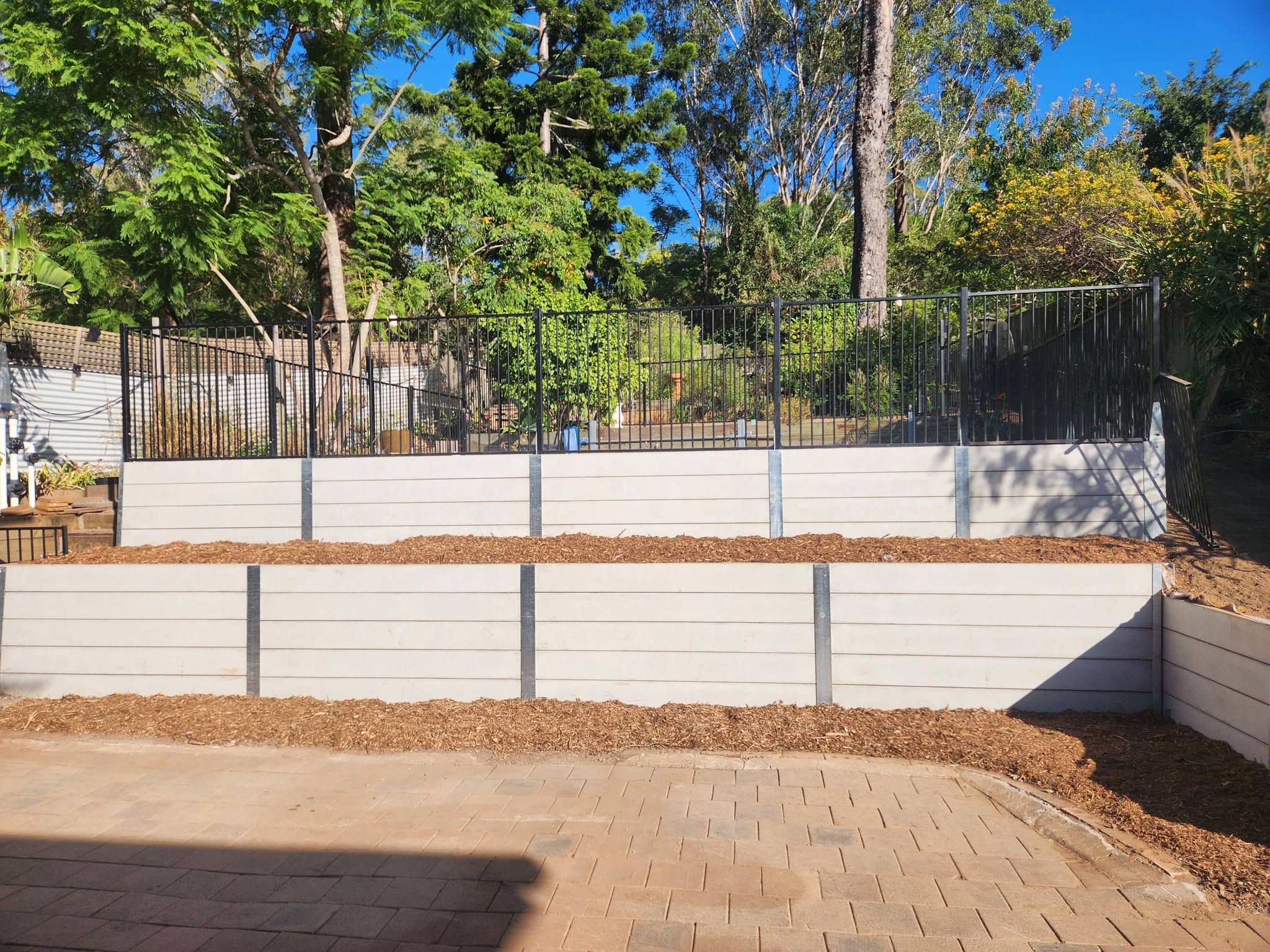 Tiered concrete retaining wall with black metal pool fence