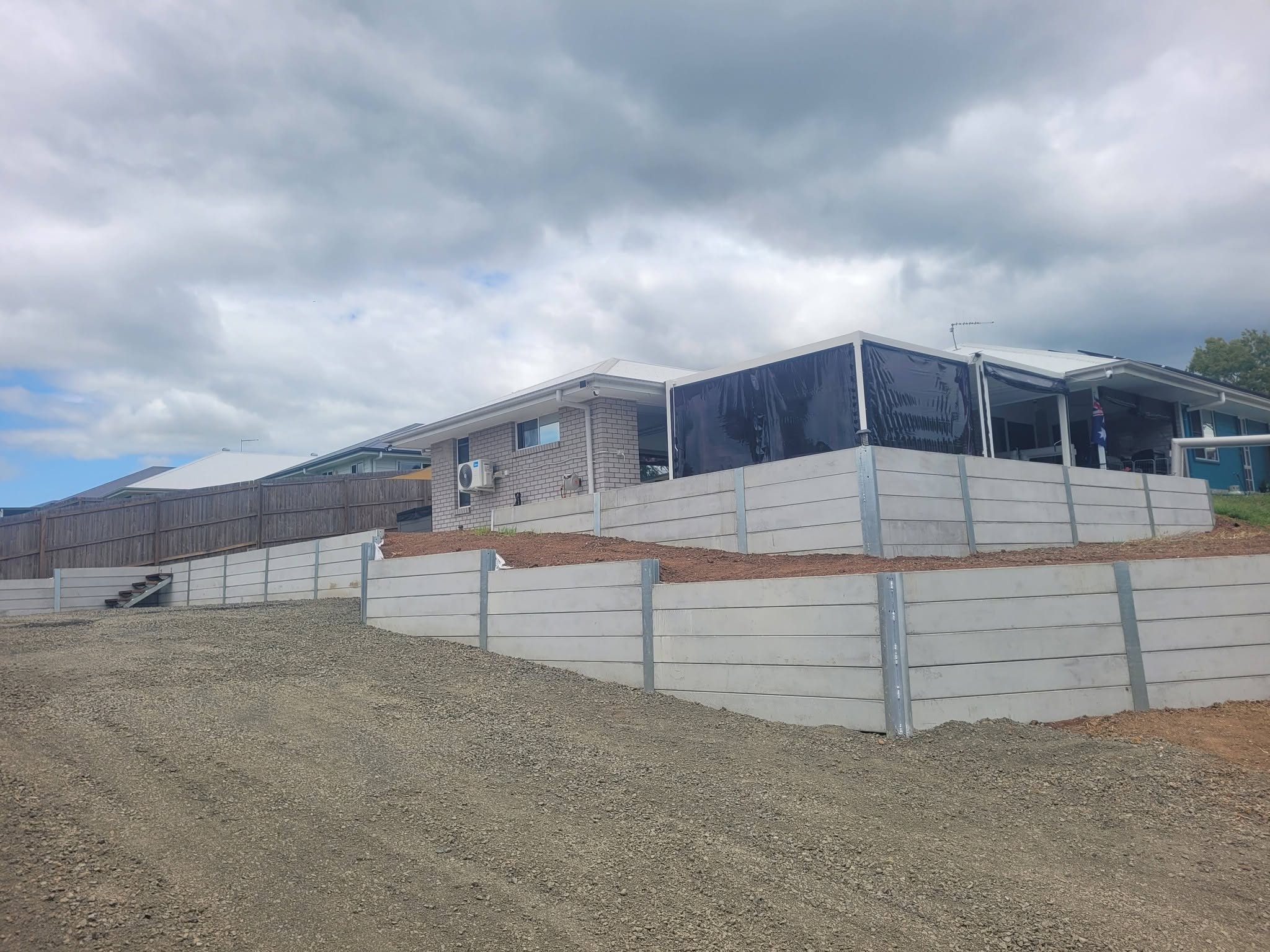 Large tiered concrete retaining wall across a sloped residential block
